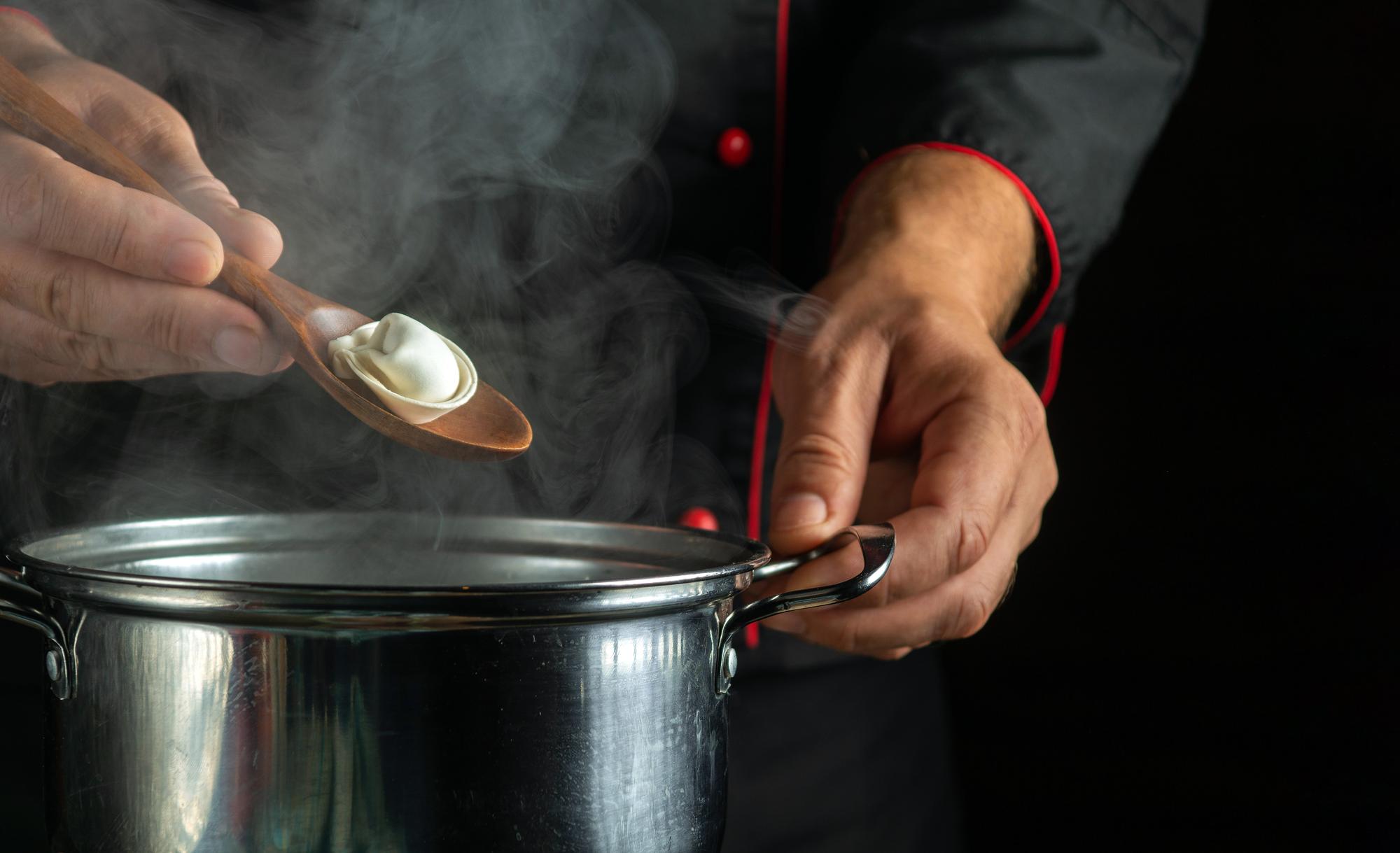 Chef hands preparing sauce over stove